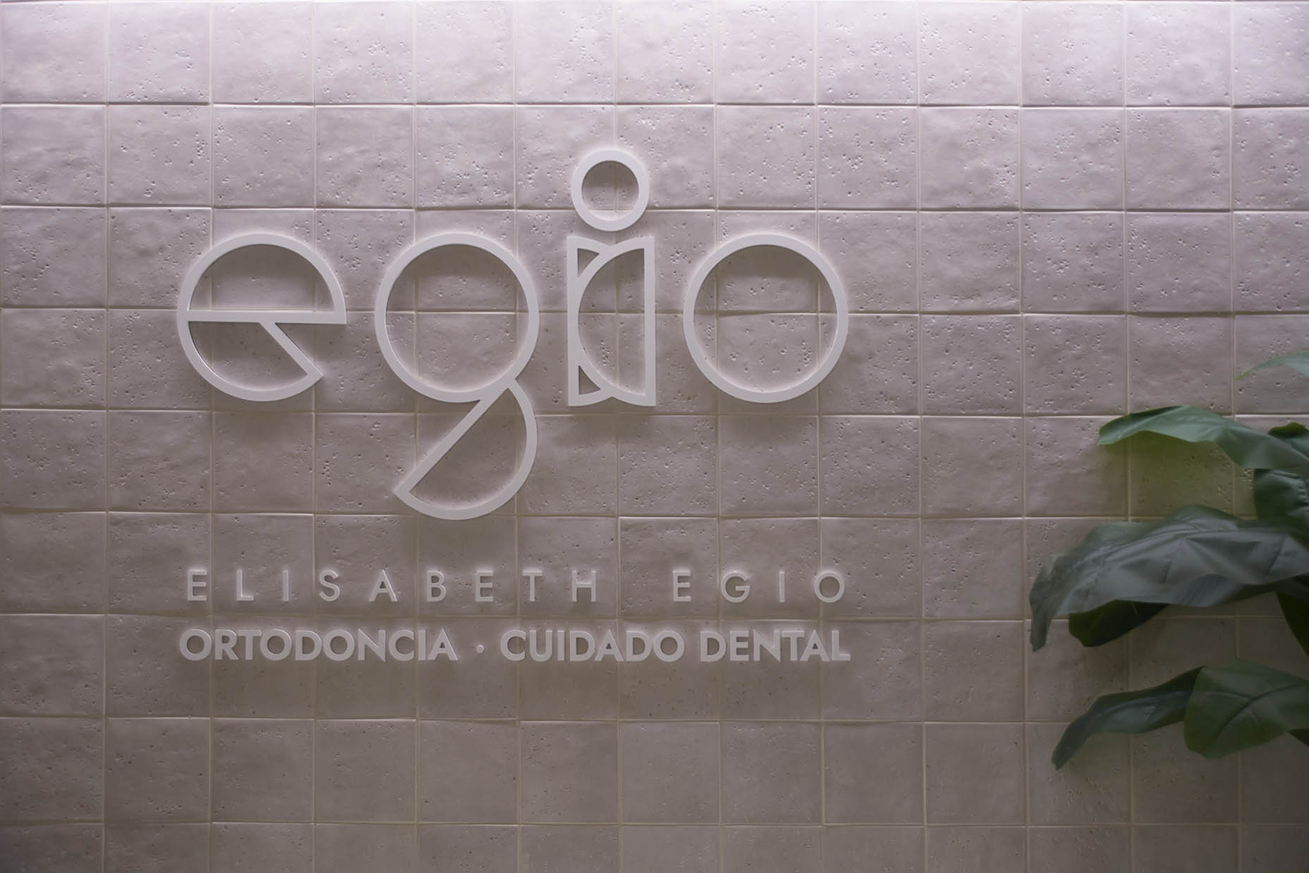 Logotipo corporeo clínica dental Elisabeth Egio, sobre pared revestida de azulejo