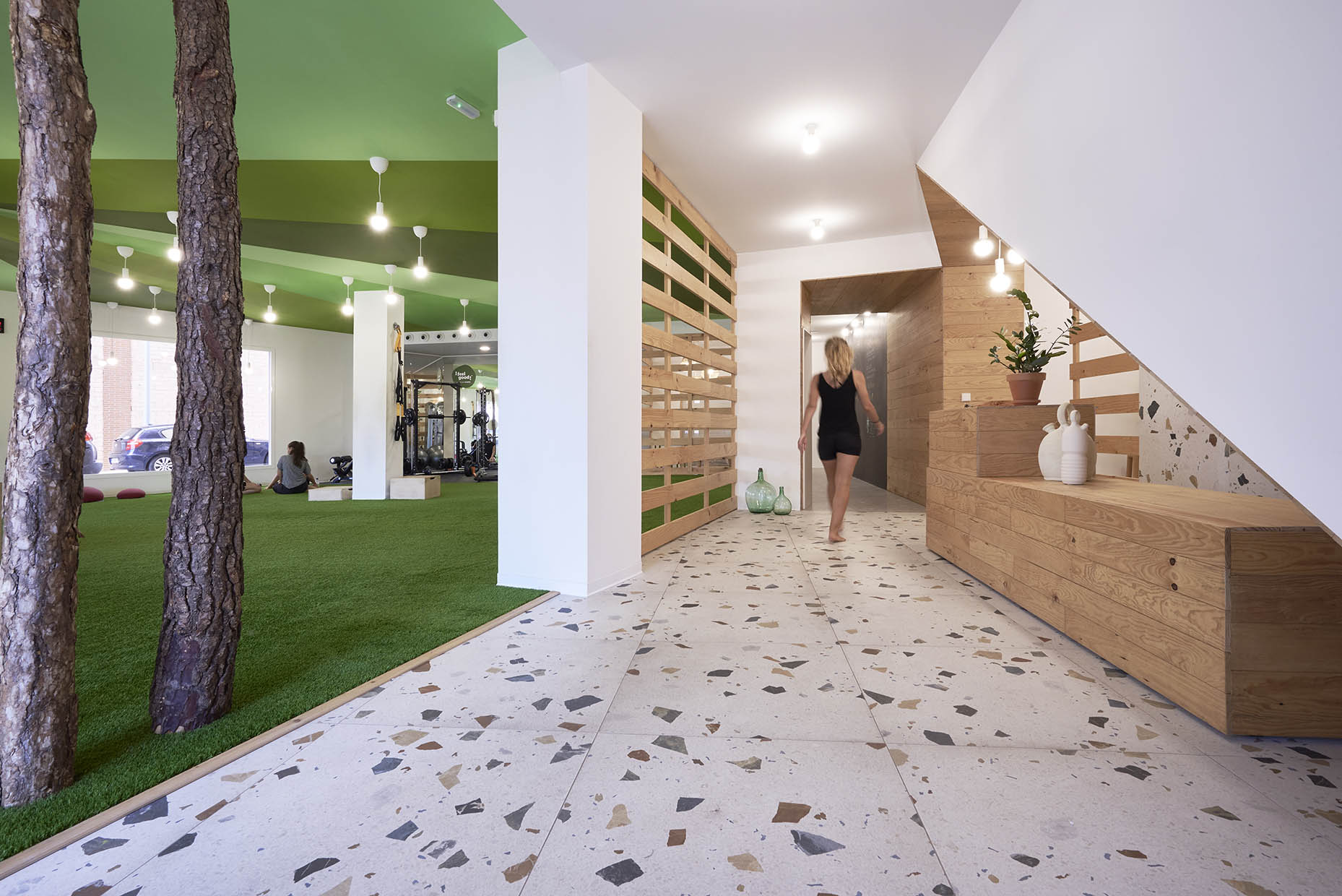 Espacio de entrenamiento con una estética natural y relajante. El suelo está cubierto de césped artificial, integrando elementos que evocan un entorno al aire libre.