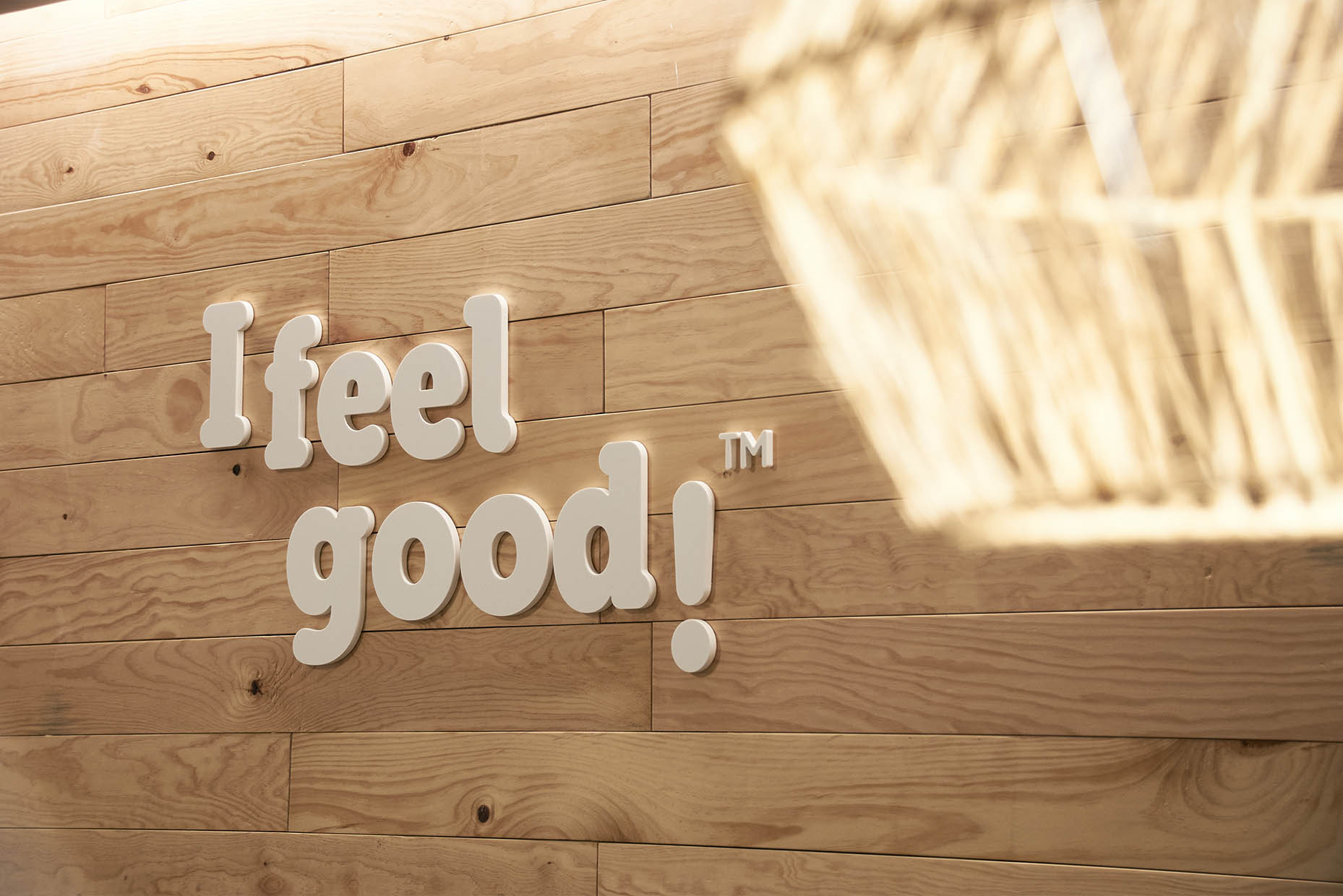 Logotipo corpóreo "I feel good" sobre pared de listones de madera dentro de gabinete de fisioterapia
